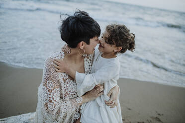 Happy woman embracing daughter at beach - GMLF01379