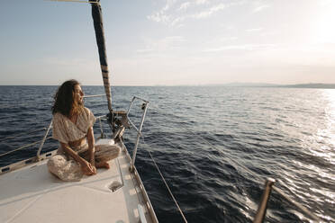 Frau sitzt auf Segelboot bei Sonnenuntergang - GMLF01381
