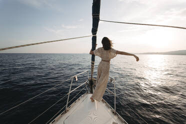 Frau mit erhobenem Arm auf Segelboot stehend - GMLF01385