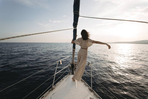 Frau mit erhobenem Arm auf Segelboot stehend - GMLF01385