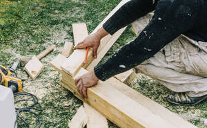 Zimmermann beim Anpassen von Holz auf Gras - VSNF00647