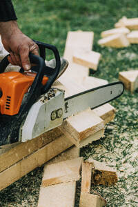 Hand eines Zimmermanns, der mit einer Kettensäge Holz schneidet - VSNF00650