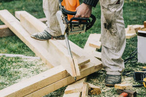 Zimmermann schneidet Holzbretter mit Kettensäge - VSNF00651