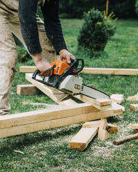 Carpenter cutting wooden planks with chainsaw machine - VSNF00652