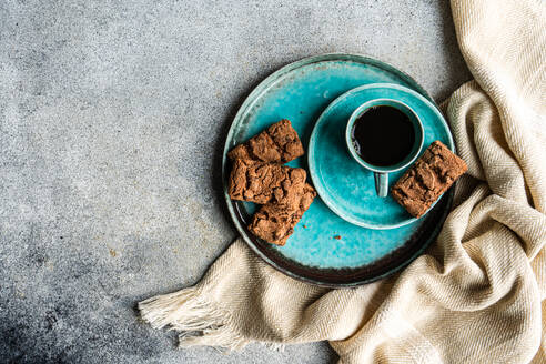 Von oben Keramikteller mit frisch gebackenen Schokolade Cookies in der Nähe von schwarzen Kaffee trinken in einem Becher auf Beton Hintergrund - ADSF43557