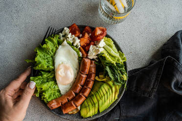 Healthy ketogenic lunch plate with vegetables, fried egg and sausages served on the concrete plate - ADSF43559