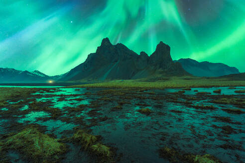 Erstaunliche Ansicht der grünen Aurora Borealis leuchtenden in den Nachthimmel über schneebedeckten Bergkamm mit schwarzem Sand Stockness Strand und Vestrahorn Berg im Hintergrund in Island - ADSF43662