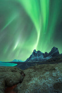 Erstaunliche Ansicht der grünen Aurora Borealis leuchtenden in den Nachthimmel über schneebedeckten Bergkamm mit schwarzem Sand Stockness Strand und Vestrahorn Berg im Hintergrund in Island - ADSF43664