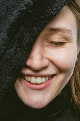 Headshot of confident cheerful young female model with blue eyes covering half face with eyes closed - ADSF43694