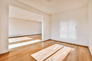 Innenraum eines geräumigen Zimmers mit weißen Wänden und Holzboden in einer modernen Wohnung - ADSF43725