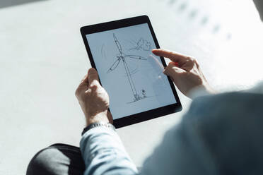 Businessman with wind turbine drawing on tablet PC in office - JOSEF18134