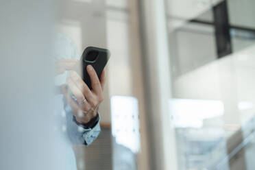 Businessman using smart phone seen through glass - JOSEF18138