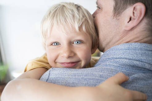Father kissing and hugging son at home - NJAF00315