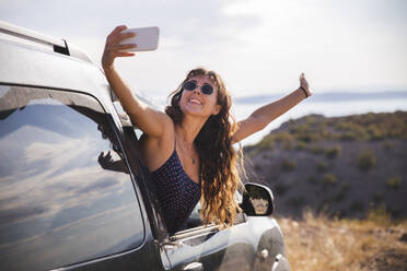 Fröhliche Frau, die einen Moment mit ihrer Smartphone-Kamera in einem Selfie festhält - PCLF00312