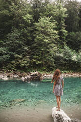 Young woman standing on rock in front of river - PCLF00329