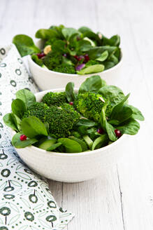 Two bowls of green salad with broccoli, corn salad, cashews, cucumber and various seeds - LVF09301