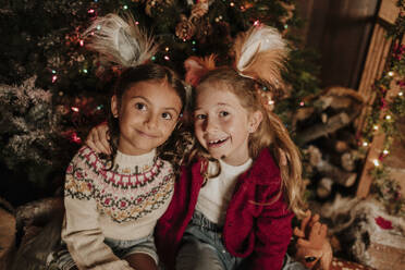 Nachdenklich lächelnde Schwestern sitzen an Weihnachten zusammen - GMLF01391