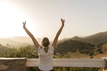 Carefree woman with arms raised enjoying at sunset - VIVF00471