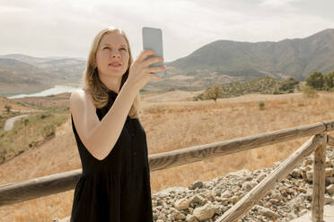 Frau fotografiert mit Smartphone an einem sonnigen Tag - VIVF00504