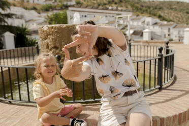 Happy mother making finger frame with daughter on sunny day - VIVF00515