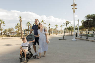 Glückliche Familie beim Spaziergang am Ufer an einem sonnigen Tag - VIVF00534