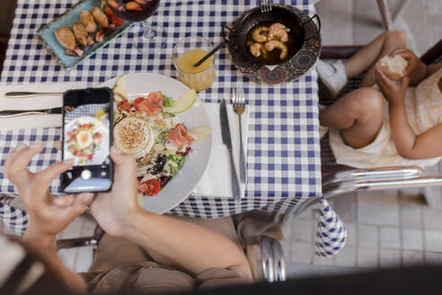 Frau fotografiert Essen im Restaurant mit ihrem Smartphone - VIVF00548