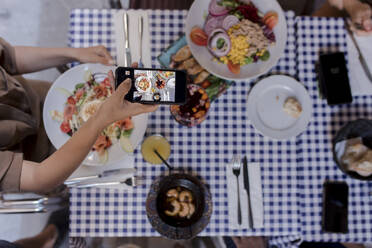 Young woman photographing food through smart phone - VIVF00550