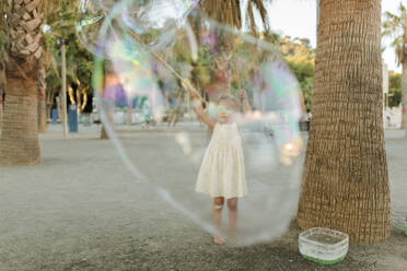 Mädchen spielt mit großer Seifenblase - VIVF00560