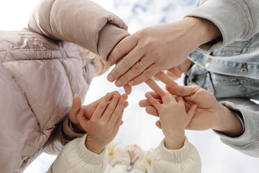 Vater und Töchter stapeln die Hände unter dem Himmel zusammen - SIF00690