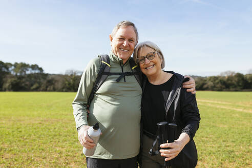 Lächelnder älterer Mann mit Arm um eine Frau, die in einer grünen Landschaft steht - EBSF03066