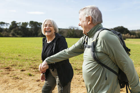 Happy senior couple holding hands and walking together in fields - EBSF03071