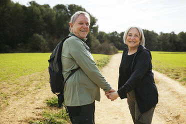 Glückliches wanderndes älteres Paar hält Hände in der Natur - EBSF03072