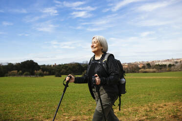 Lächelnde ältere Frau beim Wandern an einem sonnigen Tag - EBSF03075