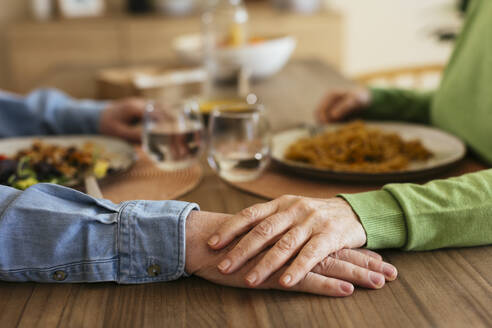 Senior woman stacking hand on man at dining table - EBSF03101