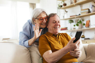 Happy senior couple on video call through smart phone at home - EBSF03117