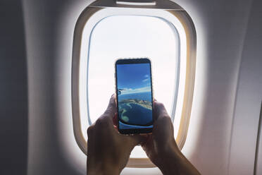Man taking photo through airplane window - PNAF05157