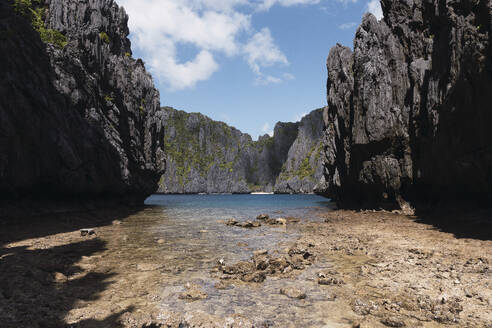 Tranquil view of beach amidst rocky cliff - PNAF05161