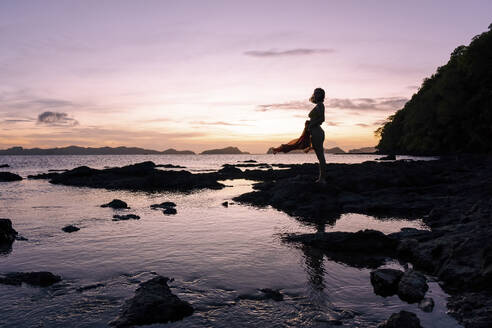 Silhouette of woman standing on beach at dusk - PNAF05196