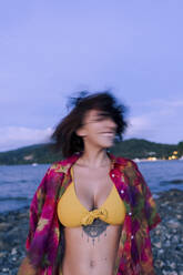 Junge Frau dreht den Kopf am Strand in der Abenddämmerung - PNAF05199