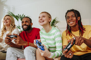 Junge Männer und eine Frau spielen ein Videospiel mit einem Freund zu Hause - MDOF00941