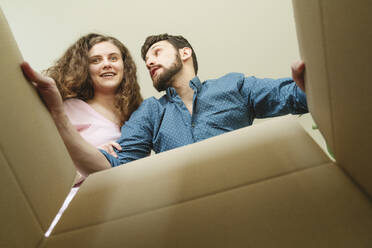 Glückliches junges Paar beim Öffnen eines Kartons in der neuen Wohnung - OSF01502