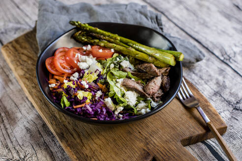 Bowl of salad with steak, asparagus, tomatoes, shredded red cabbage, lettuce and feta cheese - SBDF04609