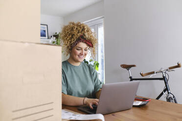 Happy young businesswoman working on laptop at desk - ASGF03480
