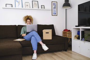 Smiling businesswoman working on laptop at home - ASGF03510