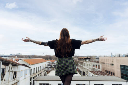 Woman with arms outstretched standing on building terrace - MEUF09016