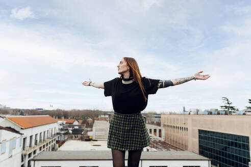 Thoughtful woman standing with arms outstretched in front of sky - MEUF09017