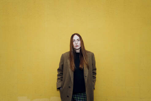 Redhead woman standing in front of yellow wall - MEUF09037