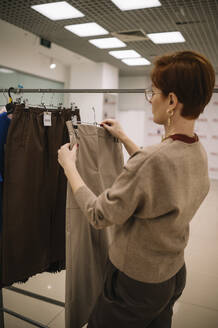 Frau sieht sich im Laden Kleidung an - ANAF01157