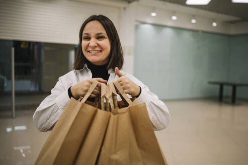Lächelnde Frau mit Einkaufstüten - ANAF01163