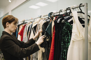 Store owner examining clothes in store - ANAF01181